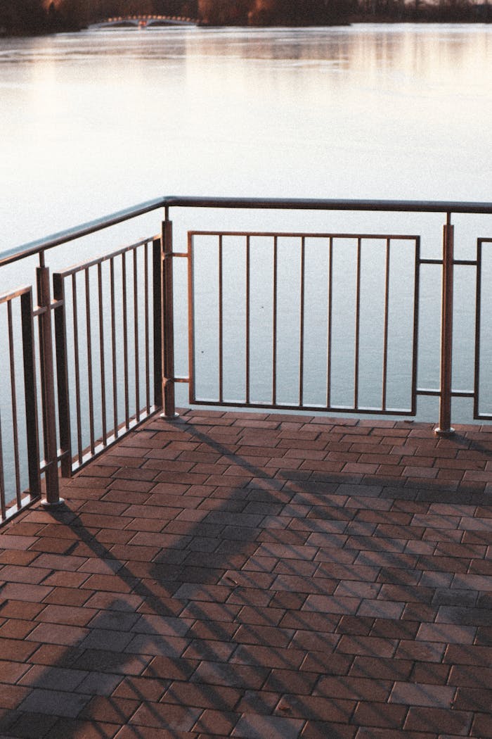 Serene water view with metal railings at sunset, featuring warm tones and reflections.