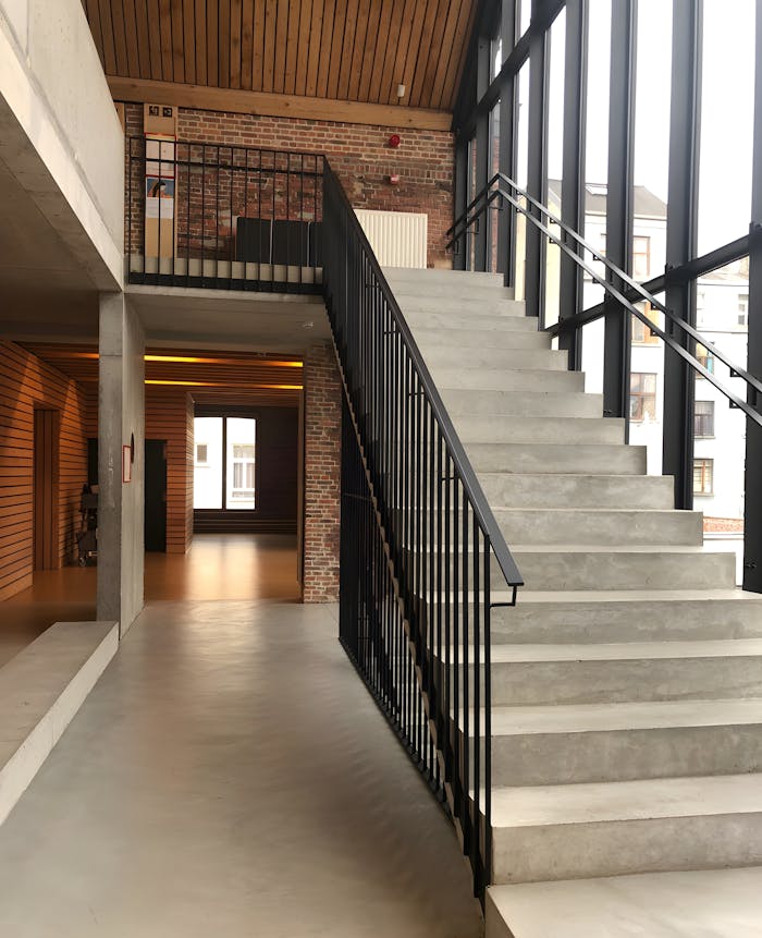 A modern staircase in an industrial-style interior with brick and glass elements.
