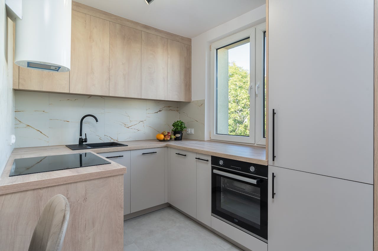 Bright minimalist kitchen with light wood cabinetry and modern appliances.