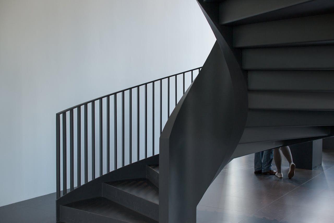 Sleek modern spiral staircase in a minimalist indoor space with natural lighting.